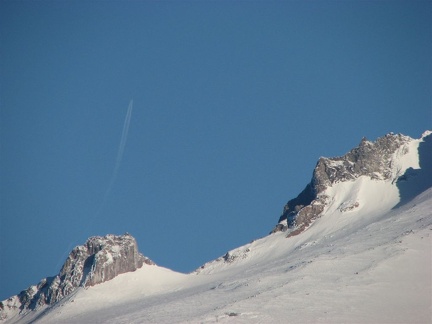 Closeup of Mt. Hood with a jet flying south leaving a contrail above Illumination Rock.